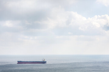 Obraz premium A big cargo ship in the sea or ocean floats on the waves against the background of a large sky.