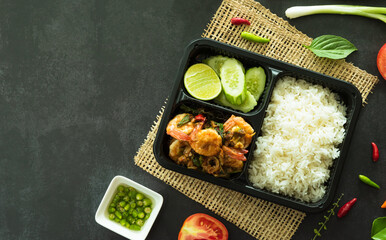 Top view of stir fried basil with shrimp, a famous Thai street food served in box for delivery food concept.