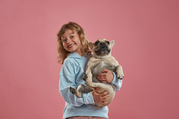 Happy little girl hold and hug French bulldog