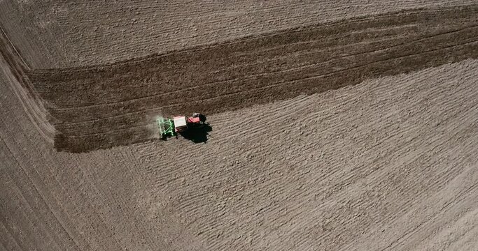 view from above and lift the drone up from the tractor that cultivates the oran field, in the view of two oran lanes. agricultural complex, soil preparation in spring. sunny day