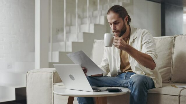 Man managing finance with laptop and papers at home