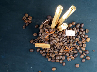 Mug with coffee beans, cinnamon and star anise. Isolated on black vintage background. The concept of aromas and spices, comfort and warmth. Flat lay