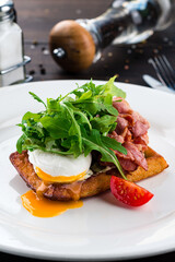 healthy breakfast poached egg with bacon and arugula