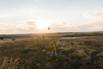 A happy boy with his family flies a kite and spends time together in the fresh air. Happy childhood and outdoor recreation with the whole family.