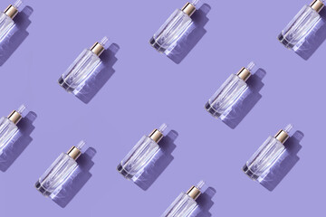 Cosmetic product, beautiful bottle with pipette on a trendy purple background, sunlight creates shadows and reflections. Demonstrating very peri, color of 2022 year.