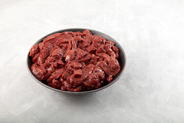 Pieces of raw beef liver in dark plate. By-products contain protein, iron and trace elements