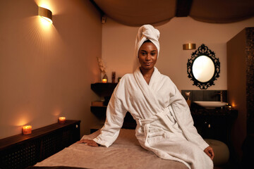 Black girl on massage table and looking at camera - obrazy, fototapety, plakaty