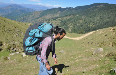 Side view of a male tourist carrying parachute backpack, walking in beautiful mountain of Himachal...