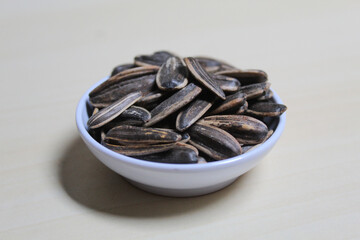 Pile of sunflower seed on a small bowl. Sunflower seed with striped shell.