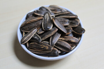 Pile of sunflower seed on a small bowl. Sunflower seed with striped shell.
