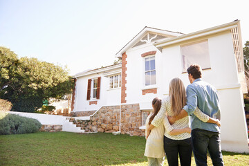 Welcome home. A family standing outdoors admiring their new home.