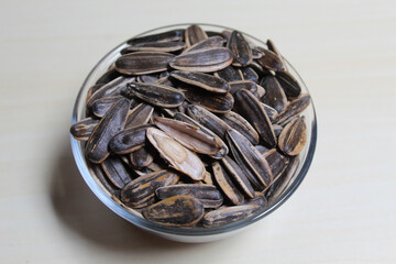 Pile of sunflower seed on a small bowl. Sunflower seed with striped shell.