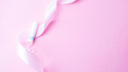 Tampons feminine hygiene. Pink ribbon with menstrual tampon on pink background. Sanitary hygiene concept. Menstruation feminine period. Menstruation, critical days, zero waste, eco, ecology banner.
