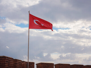 Alanya, turkey, winter walk by mediterranean sea. Kizil Kule tower on peninsula of Alanya. Famous tourist destination with high mountains. Part of ancient old castle with turkish flag..