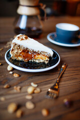 Beutifly decorated Hazelnut caramel cake on wooden background with coffee, coffee shop food.