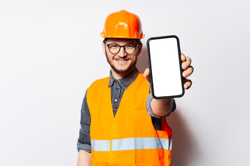 Studio portrait of construction worker holding smartphone with blank screen.