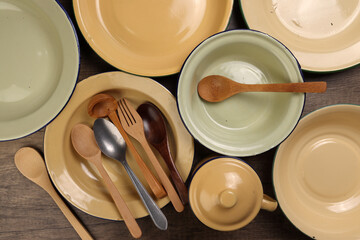 Varity of wooden metal spoon on enamel tin food plate pot bowl retro vintage tableware dinnerware on rustic wood background top view