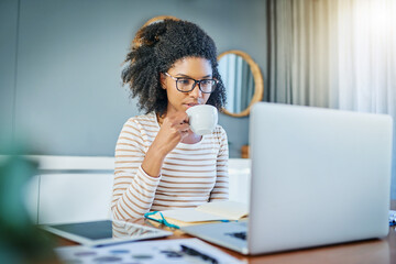 Shes her own boss. Shot of a young woman working on a laptop at home.