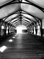 Grayscale shot of a bridge with closed cover and sunlight on the ground