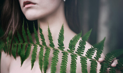 girl in the forest naked collarbone and neck with a fern