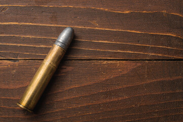 Overhead view of large rifle bullet on wood