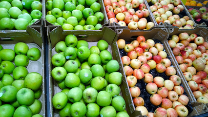 Fruits, green and red apples in boxes on supermarket shelves. Retail industry. Grocery store....