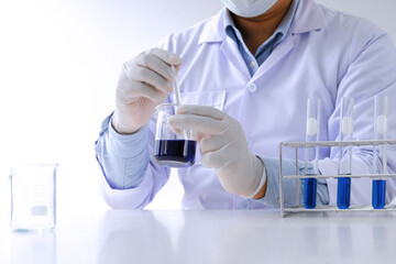 Fototapeta premium Science innovative Male medical or scientific laboratory researcher performs tests with blue liquid in laboratory. equipment science experiments technology Coronavirus Covid-19 vaccine research