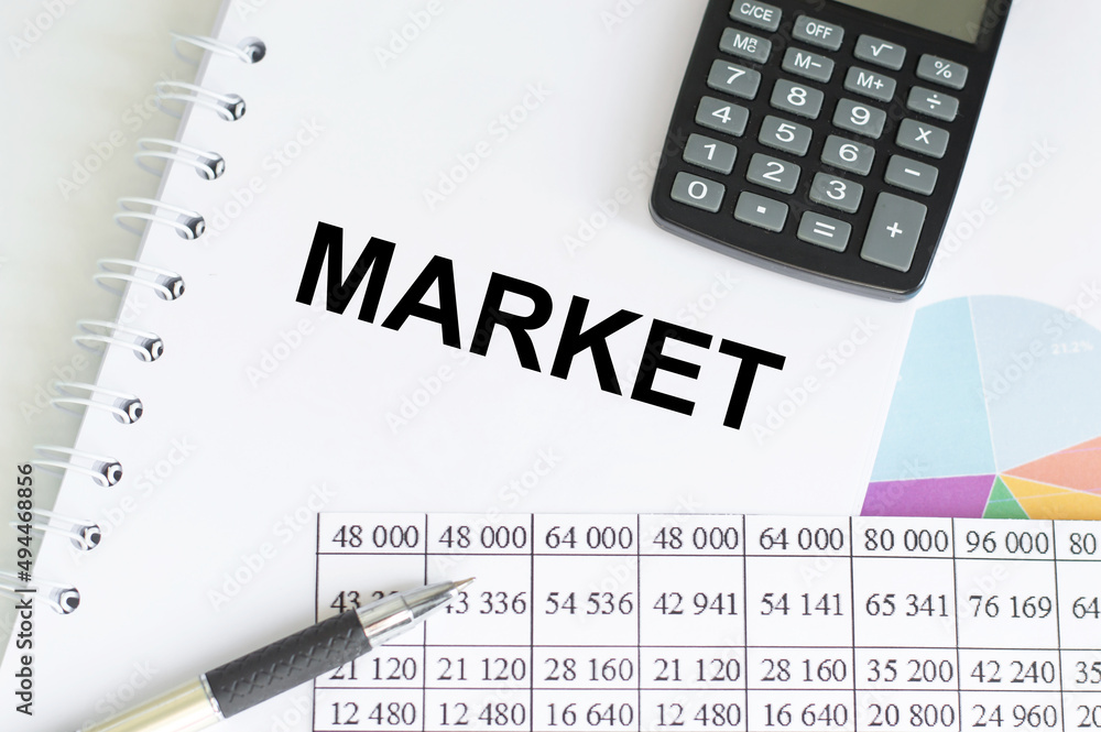 Poster market text on notepad on a table next to calculator, pen and reports