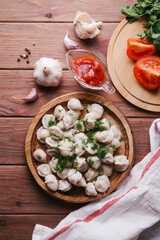 Dumplings on a wooden background with herbs and tomato sauce
