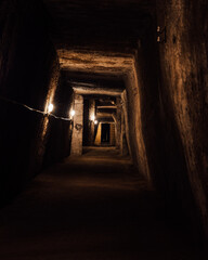 Vertical shot of an underground city or catacomb corridor wirth stone walls and entrances