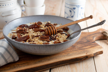 Yogurt with pecan nuts, dates, roasted oats and honey in a bowl