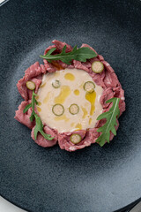 Beef vitello tonnato with capers and mustard sauce, directly above, black plate