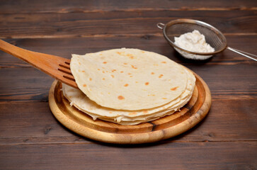 a stack of freshly baked thin pita breads on a wooden board
