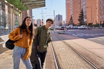 teenage couple waiting at the train or tram stop. young students with a guitar and a ukulele in its...