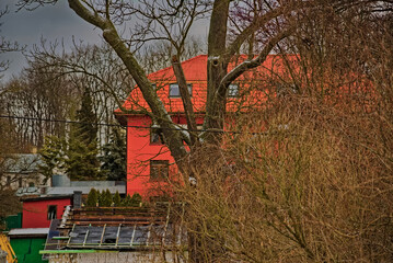 Duży dom wśród drzew i krzewów zimową porą , remont dachu na budynku gospodarczym . Na tle...