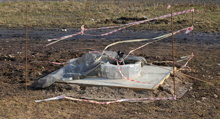 The hatch of underground communications fenced with striped tape