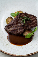 Dark beef medallion grilled with zucchini slices with brown rye sauce, fine dining posh restaurant, marble table