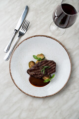 Beef fillet grilled with zucchini circles, covered with brown sweet sauce, fine dining menu, beige table