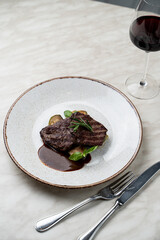 Dark beef medallion grilled with zucchini slices with brown rye sauce, fine dining posh restaurant, marble table