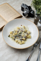 Boiled gnocchi with forest mushrooms and grated parmesan, rustic plate in gourmet restaurant, low contrast light photo