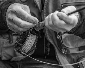 Grayscale closeup of the hands holding a fishing rod.