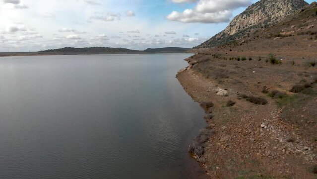 Aerial images flying at low altitude over the shore of a reservoir on a magnificent cloudy day.