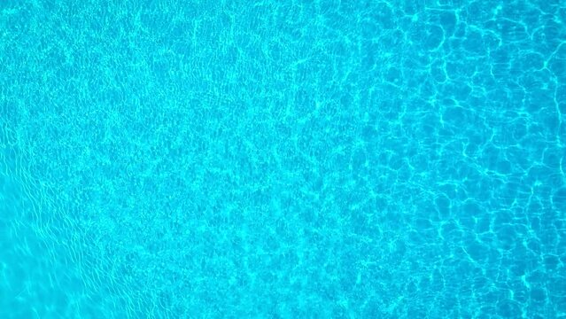 Blue water in the swimming pool with light reflections. Aerial footage