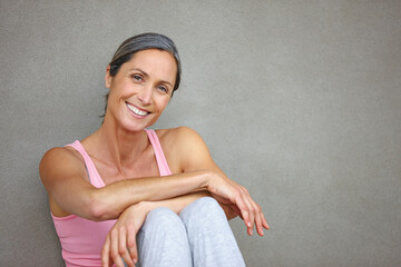 Living a healthy lifestyle. Portrait of an attractive mature woman in gymwear sitting against a...
