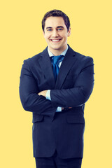 Portrait of smiling middle aged confident businessman, isolated over yellow color background. Happy business man in crossed arms pose at studio.