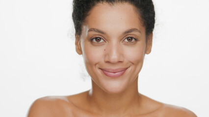 Close-up beauty portrait of young positive African American woman smiling for the camera on white background | Soft skin concept