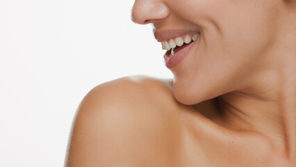 Obraz premium Horizontal big close-up of good-looking female beauty model looks aside and smiles widely on white background | Skin care concept
