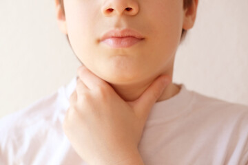 close-up of hands of child holds throat, boy of 10 years old is sick, concept of children's health,...