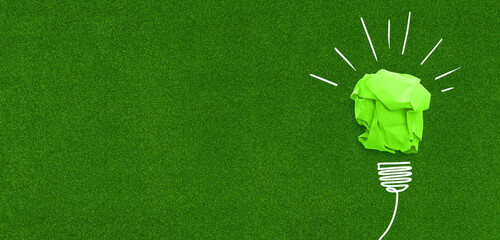 Concetto di idea green rappresentata da una lampadina verde di carta su sfondo di erba, formato banner con spazio dedicato al copy