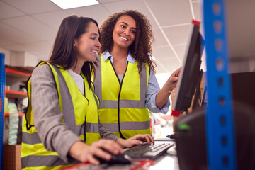 Female Staff In Busy Modern Warehouse Working On Computer Terminals